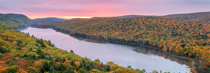 A wide river winding through a valley of dense forest with autumn foliage