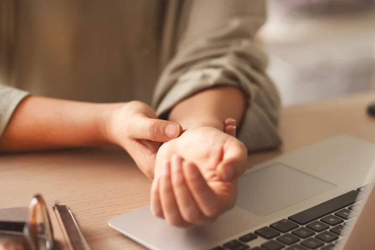 Holding a wrist where carpal tunnel numbness and tingling are felt